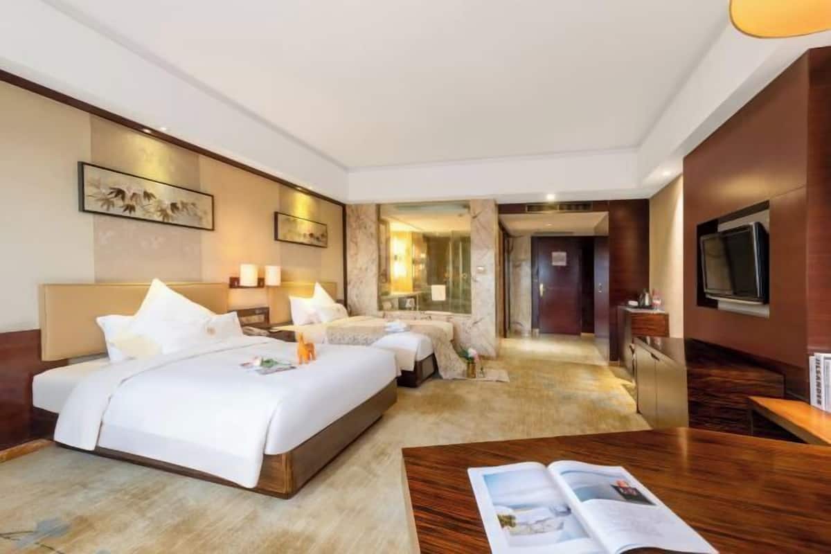 A hotel room with a large bed, a desk, a TV, and a bathroom visible through an open door.