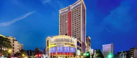 A multi-story hotel with a prominent vertical structure and a brightly lit ground-level building.