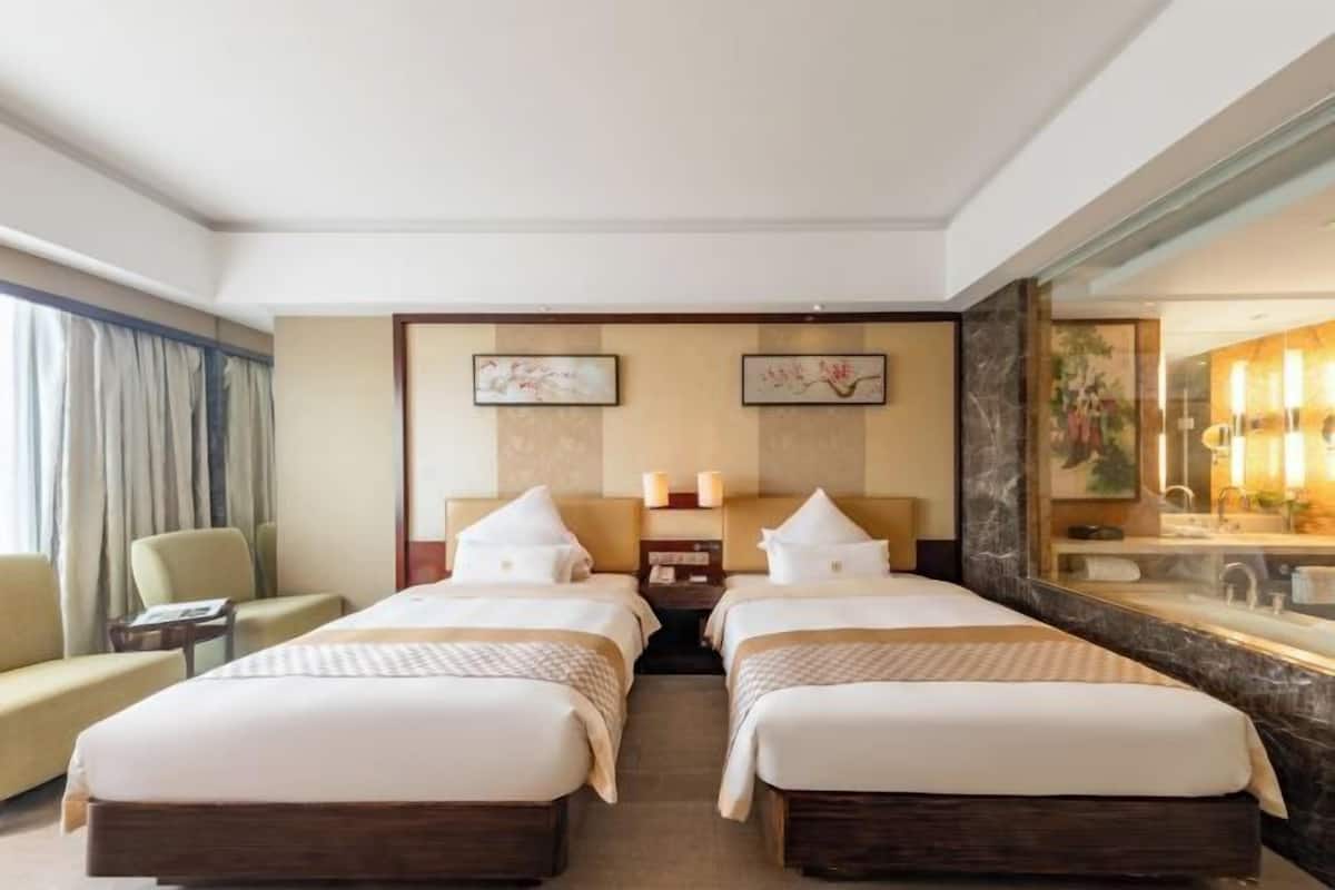 A hotel room with two beds, a sofa, a small table, and a large mirror.