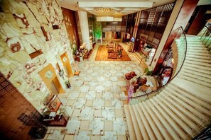 Un hall d’hôtel avec un escalier en colimaçon, un comptoir d’accueil et un sol à motifs.