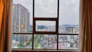 A window with a view of a cityscape, including buildings and a mountain range.