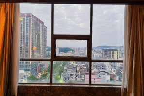 Una ventana con vista a un paisaje urbano, incluyendo edificios y una cadena montañosa.