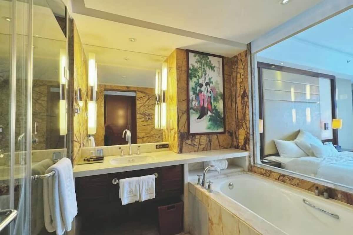 A modern bathroom with a large mirror, a bathtub, and a shower.