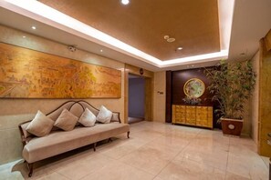 Un vestíbulo con un sofá, un cuadro grande en la pared, una planta en maceta y un aparador decorativo.
