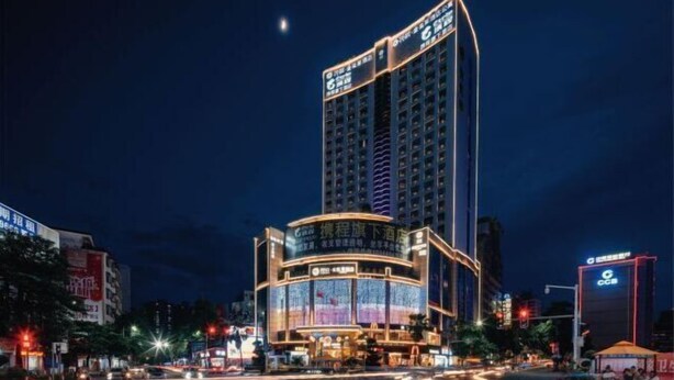 A high-rise hotel with illuminated signage and a prominent entrance. - Floral Hotel · YunFu City King Royal Hotel (Yunfu)