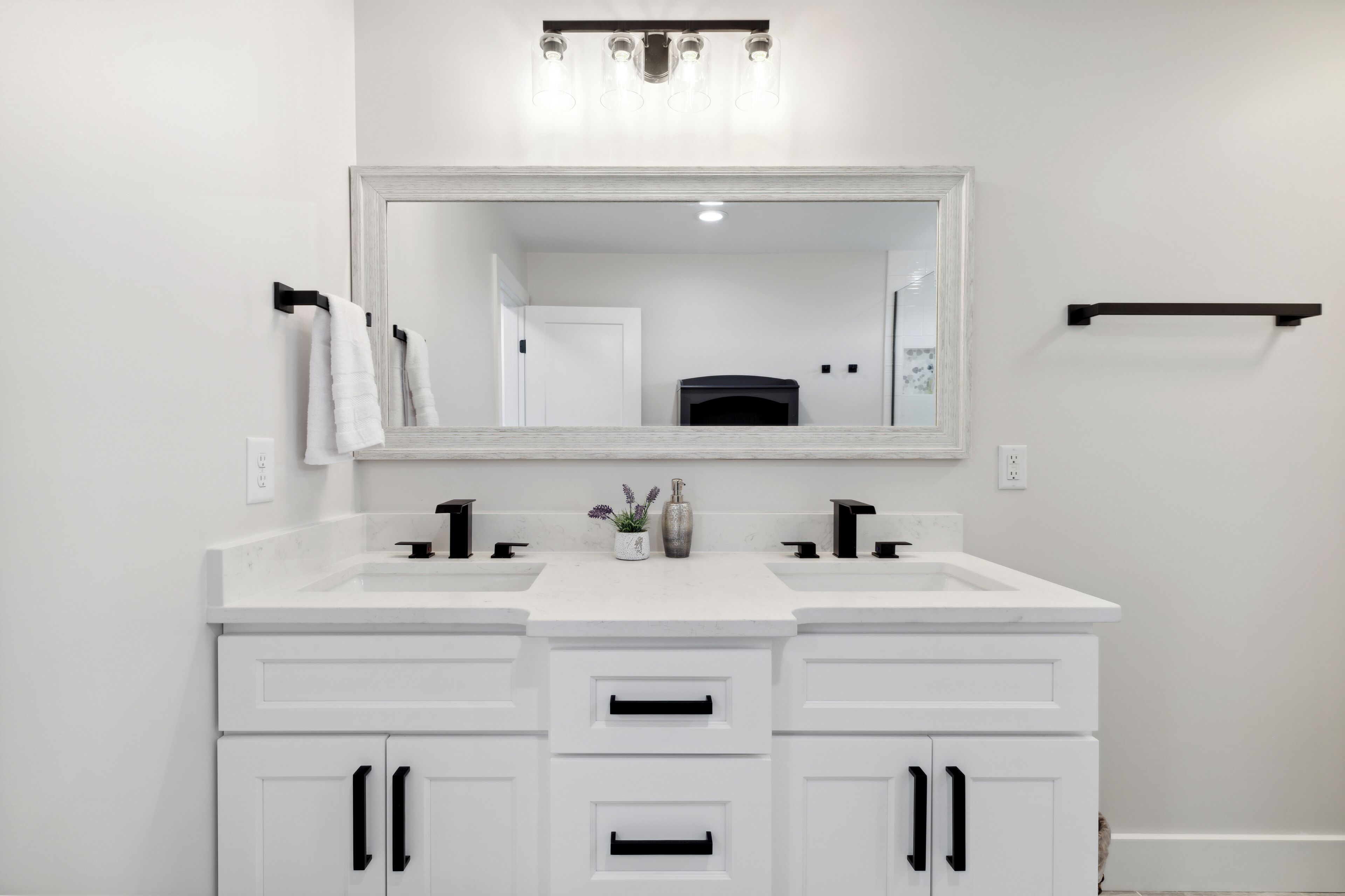 Un bagno con due lavabi, uno specchio grande e un portasciugamani nero.