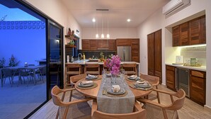 A modern kitchen with wooden cabinets, a central island, and a dining area with a table set for six. - Gated 3BD+Office/flex bedroom, Sleeps 8, HTD Pool, Rooftop, 2 Blks to Malecon (La Paz)