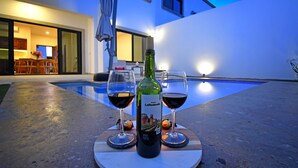 A bottle of wine and two glasses on a round table by a poolside. - Gated 3BD+Office/flex bedroom, Sleeps 8, HTD Pool, Rooftop, 2 Blks to Malecon (La Paz)