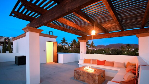 A rooftop terrace with a fire pit, white sofas, and a view of palm trees and mountains. - Gated 3BD+Office/flex bedroom, Sleeps 8, HTD Pool, Rooftop, 2 Blks to Malecon (La Paz)