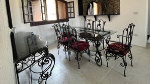 A dining area with a glass table, black metal chairs, and a large mirror on the wall. - Chalet For Rent In Marina 6 District 31 (North coast)