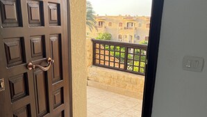 An open door leading to a balcony with a view of buildings and a railing. - Chalet For Rent In Marina 6 District 31 (North coast)