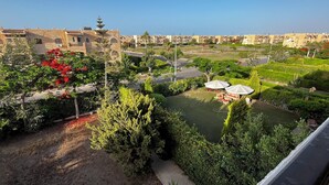 A courtyard with a lawn, seating area, and a view of surrounding buildings. - Chalet For Rent In Marina 6 District 31 (North coast)