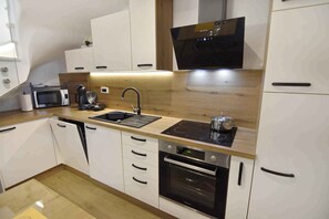 Uma cozinha moderna com armários brancos, micro-ondas, cafeteira, pia e forno.