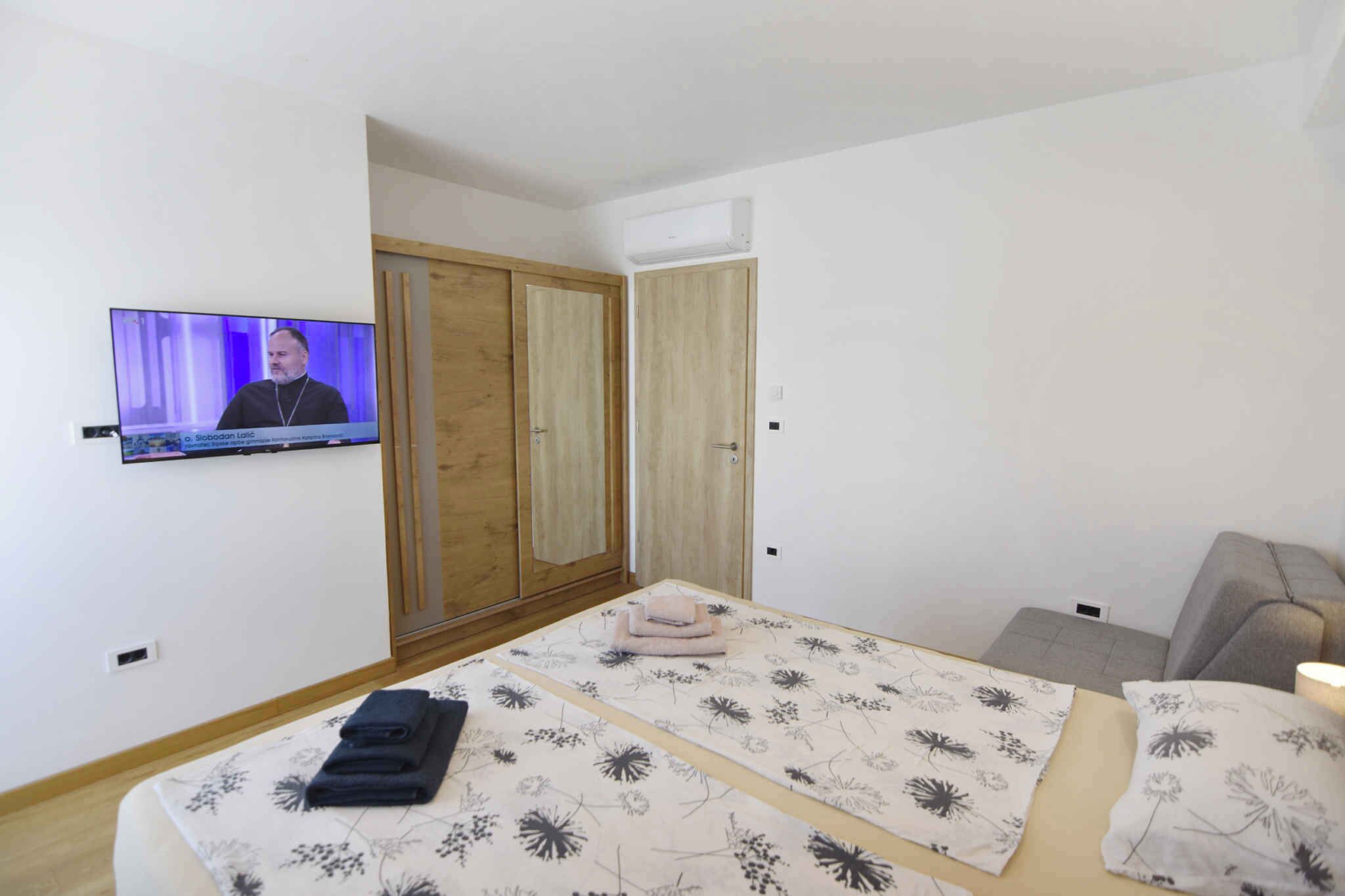 Ein Hotelzimmer mit Bett, Fernseher, Kleiderschrank und Sofa.