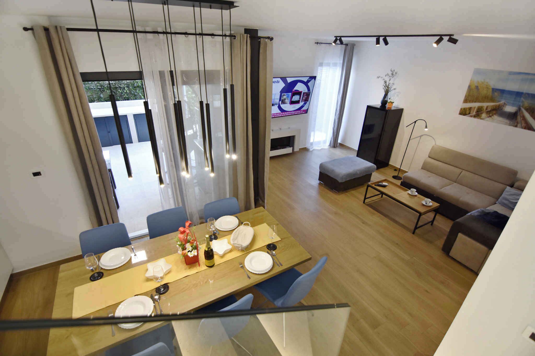 A modern living room with a dining area, a sofa, a TV, and a fireplace.