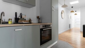 Una cocina moderna con armarios grises, horno empotrado y encimera con diversos utensilios de cocina.