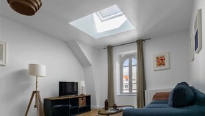 Una sala de estar moderna con tragaluz, un sofá, un televisor y una lámpara.