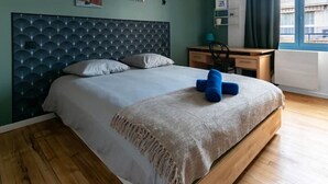 Un dormitorio moderno con una cama de madera, un cabecero de diseño geométrico, una mesita de noche y un ventanal con cortinas.