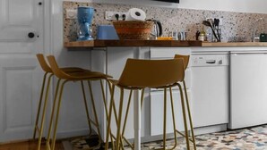 Una cocina moderna con un televisor sobre la encimera, dos taburetes de bar y un suelo con diseño.