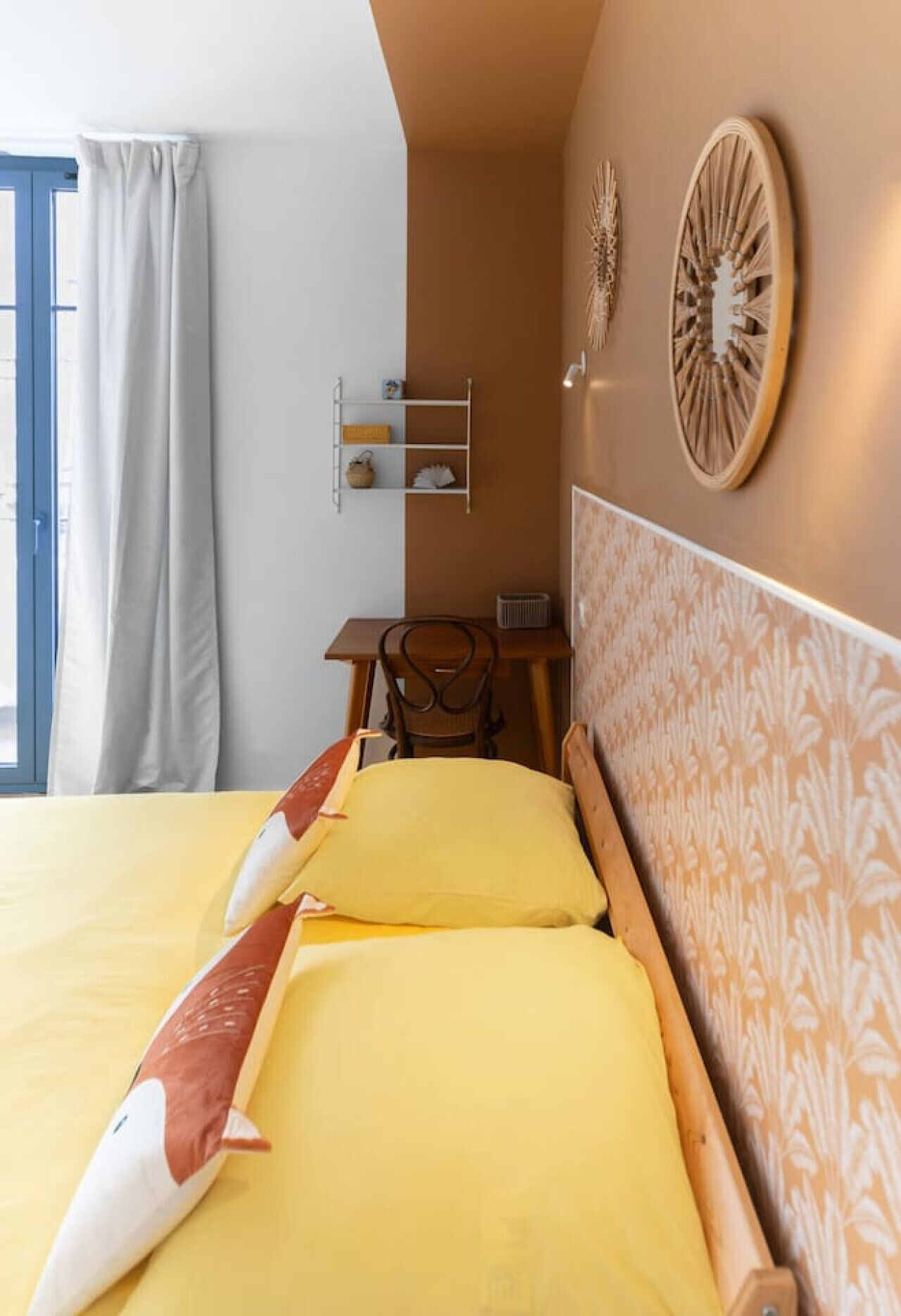 A hotel room with a bed, a desk, a chair, and a window with curtains.