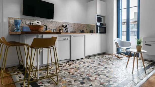 Una cocina moderna con armarios blancos, horno empotrado y un ventanal grande.
