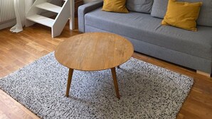 A modern living room with a grey sofa, two mustard-colored pillows, a wooden coffee table, and a white spiral staircase against the wall. - Maison calme en plein centre 2 chambres 90m2, Wifi (Clermont-Ferrand)
