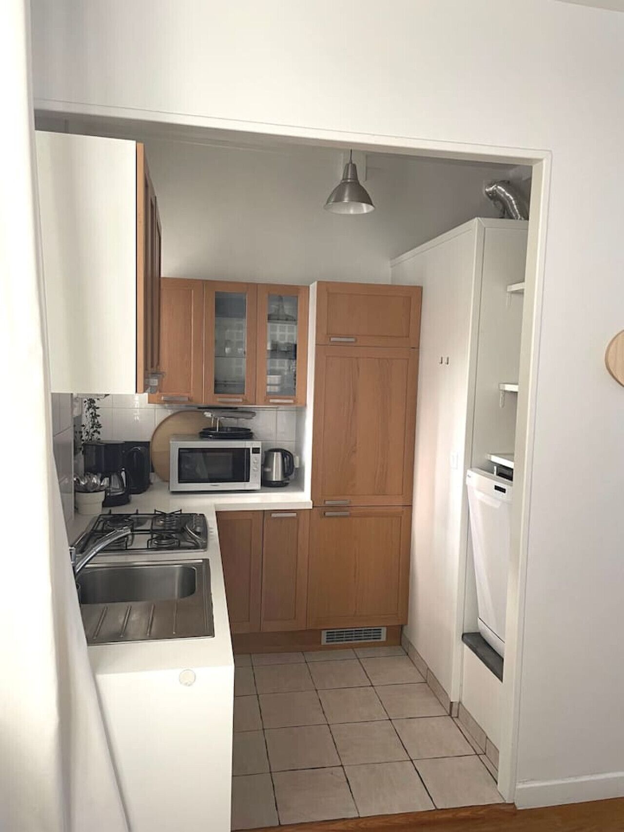Une cuisine de taille réduite, dotée de meubles en bois, d’un four à micro-ondes, d’une cuisinière et d’un réfrigérateur.