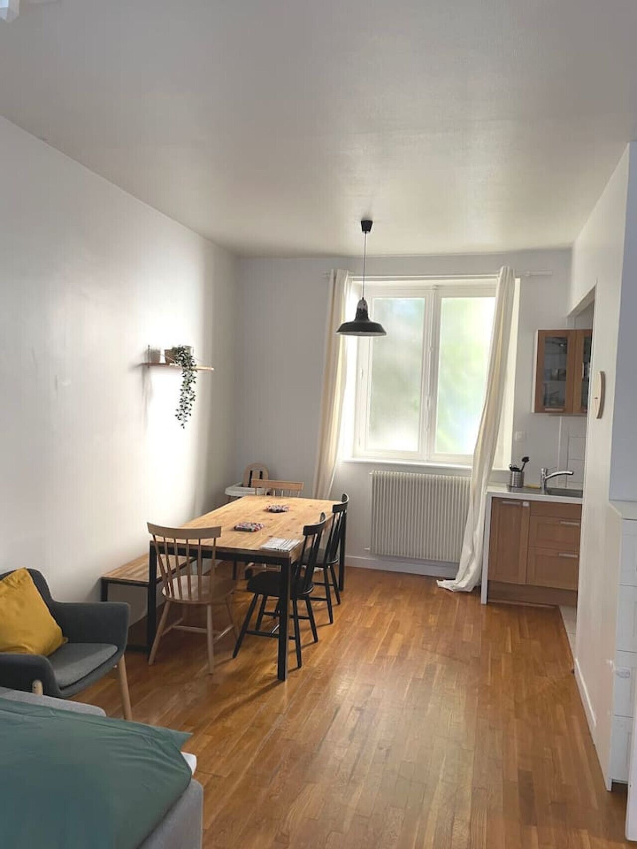 Un espace de vie compact comprenant un coin repas, une kitchenette et une fenêtre avec des rideaux.