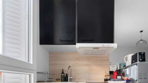 A modern kitchen with black cabinets, a white countertop, and a red hexagonal tile floor. - Magnificent apartment - City Center - Spa & Parks (Vichy)