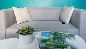 A grey sofa with patterned cushions, a white table, and a magazine titled 'VICHY'. - Magnificent apartment - City Center - Spa & Parks (Vichy)
