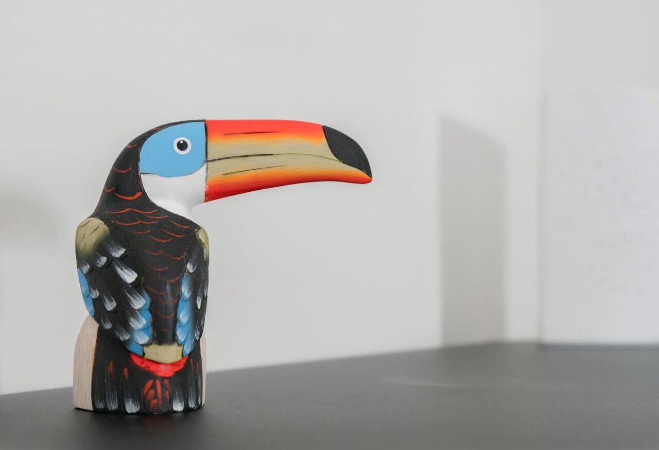 A wooden sculpture of a toucan with a colorful beak and feathers.