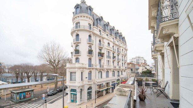 A multi-story building with a classical architectural style, featuring balconies and a corner entrance. - Superbe appartement centre-ville avec terrasse (Vichy)