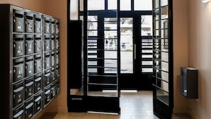 A hallway with a row of lockers on the left and a door leading to an outdoor area. - Superbe appartement centre-ville avec terrasse (Vichy)