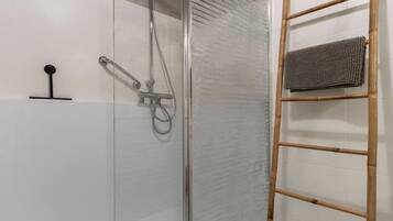 Un box de ducha moderno con puerta de cristal, una escalera de madera y baldosas de suelo estampadas.