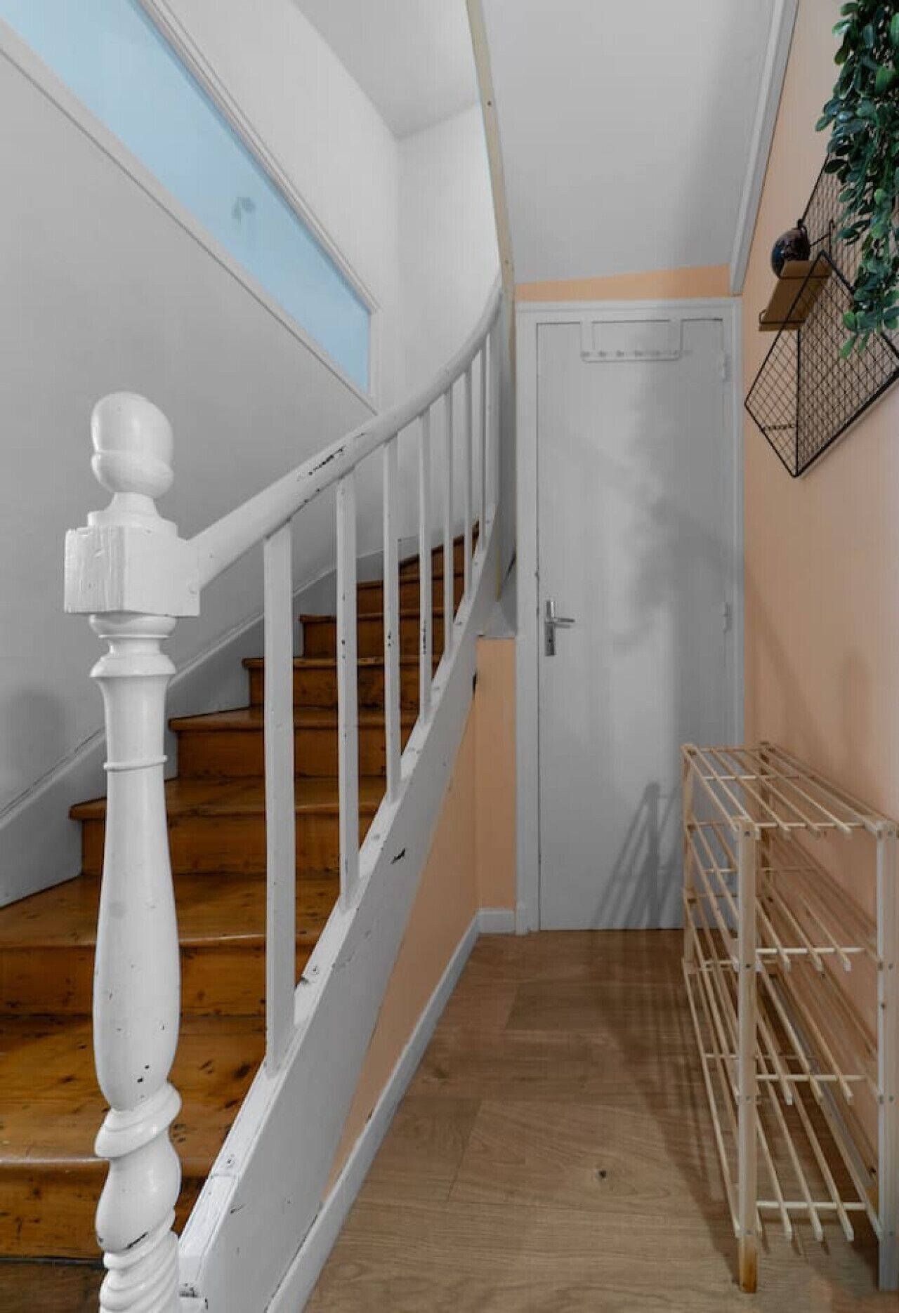 Un escalier avec des balustrades blanches et des marches en bois menant à une porte.