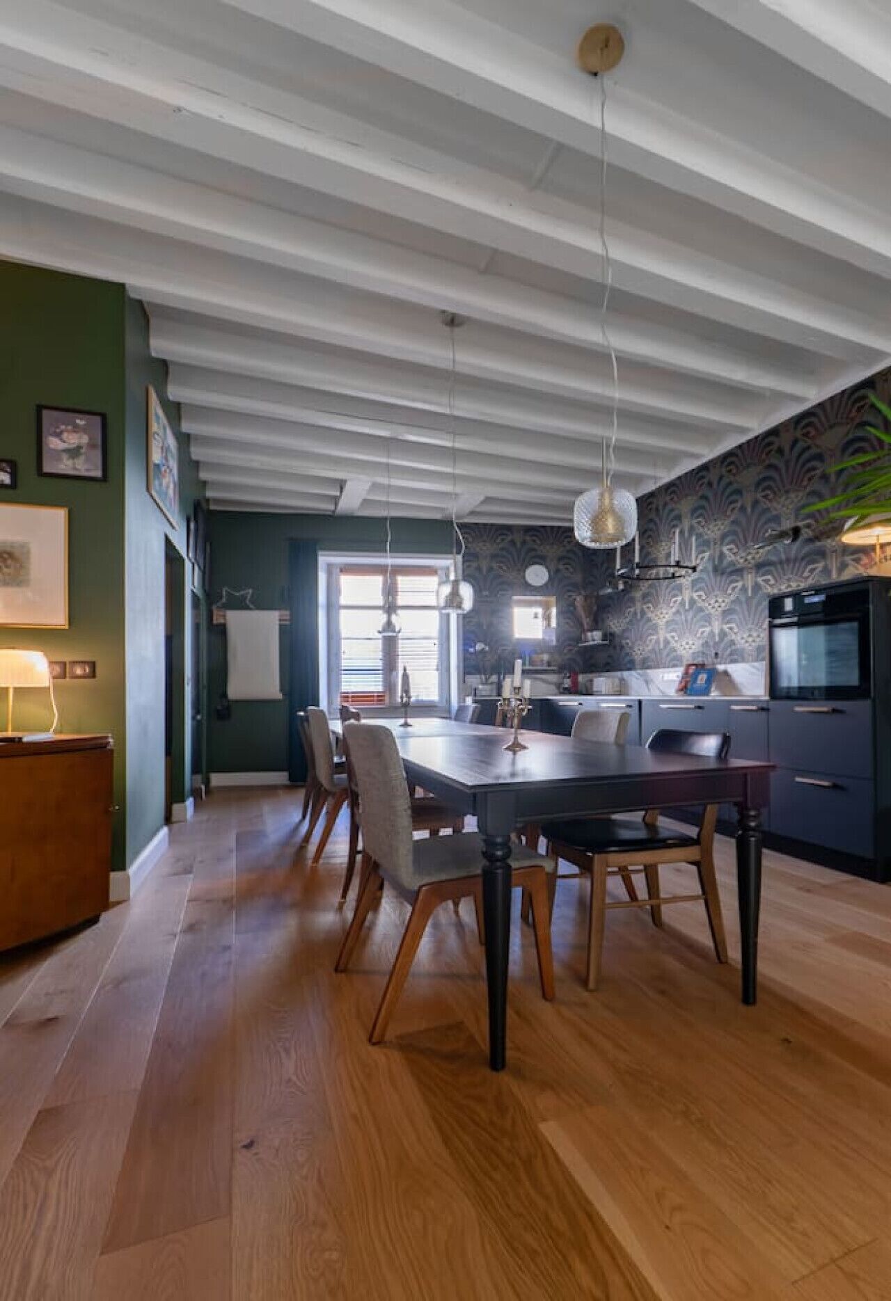 A modern kitchen with dark cabinetry, a built-in oven, and a large island with a sink.