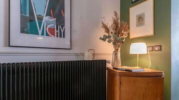 Ein Zimmer mit Heizkörper, einem Holzschrank mit Lampe und gerahmten Bildern an der Wand.