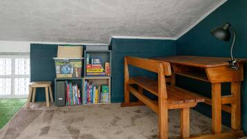 Una habitación con un escritorio de madera, una estantería y una ventana.