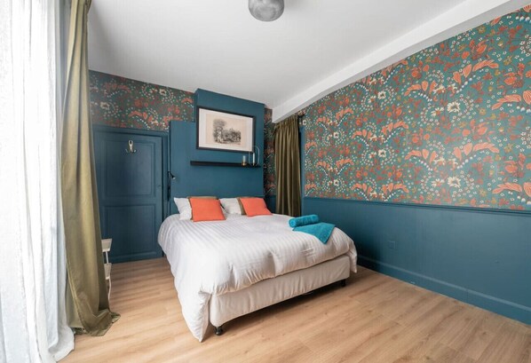 A bedroom with a bed, a blue door, and floral wallpaper. - Grande Maison Cusset - 5 rue Fourneris - Cusset (Cusset)