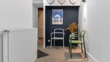 Een gang met een witte radiator, een donkerblauwe deur en een poster aan de muur.