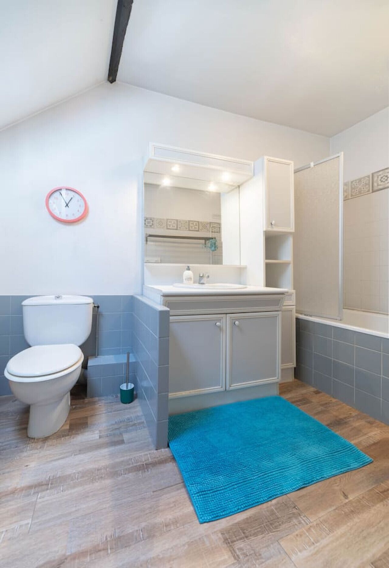 A bathroom with a toilet, sink, and mirror.