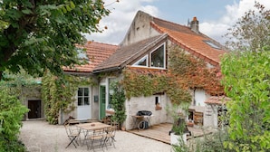 A rustic house with a tiled roof, a wooden deck, and a gravel patio. - Grande Maison design, terrasse, jardin, parking (Creuzier-le-Neuf)