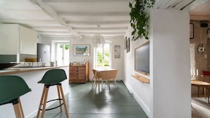 A kitchen with a dining area, wooden cabinets, a wooden table, and a hanging plant. - Grande Maison design, terrasse, jardin, parking (Creuzier-le-Neuf)