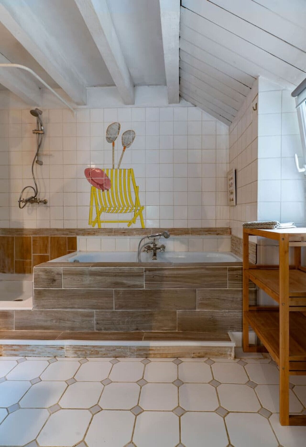 A bathroom with a large bathtub, wooden floor tiles, and a wooden shelf.