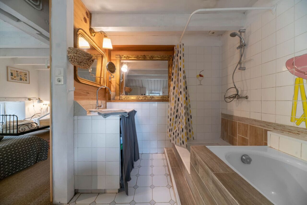 Een badkamer met een badkuip, douche en een wastafel met spiegel.