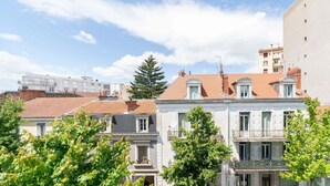 A row of traditional European-style buildings with red-tiled roofs, white facades, and balconies. - Charmant 2 pièces Centre Ville (Vichy)
