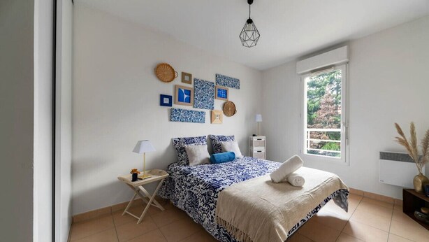 Una camera da letto con un letto, un comodino, una lampada e opere d'arte alle pareti.