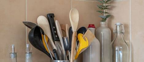 A kitchen counter with various utensils, bottles, and a plant.