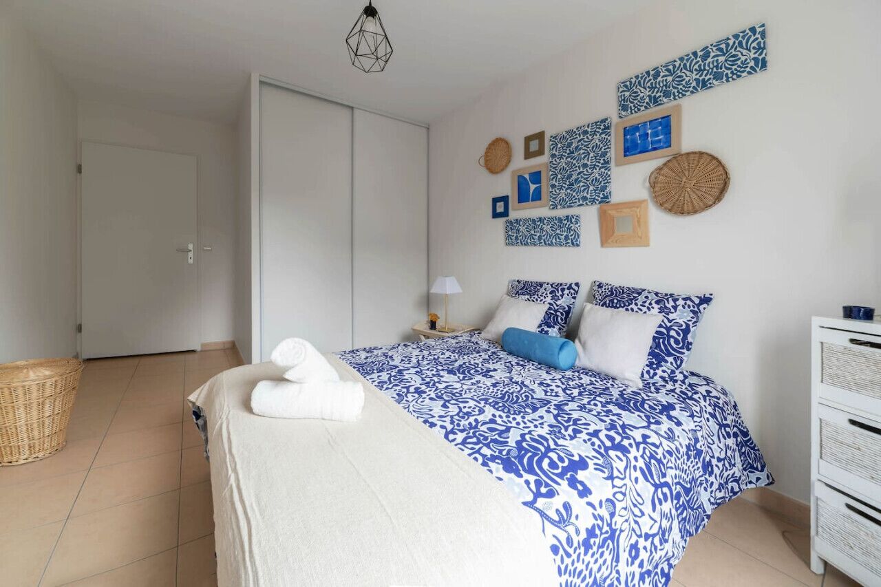 A bedroom with a bed, a nightstand, a lamp, and wall decor.