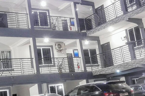 A multi-story building with balconies, a central air conditioning unit, and a fire extinguisher. - Single / Studio Room Apartment Kasoa (Kasoa)